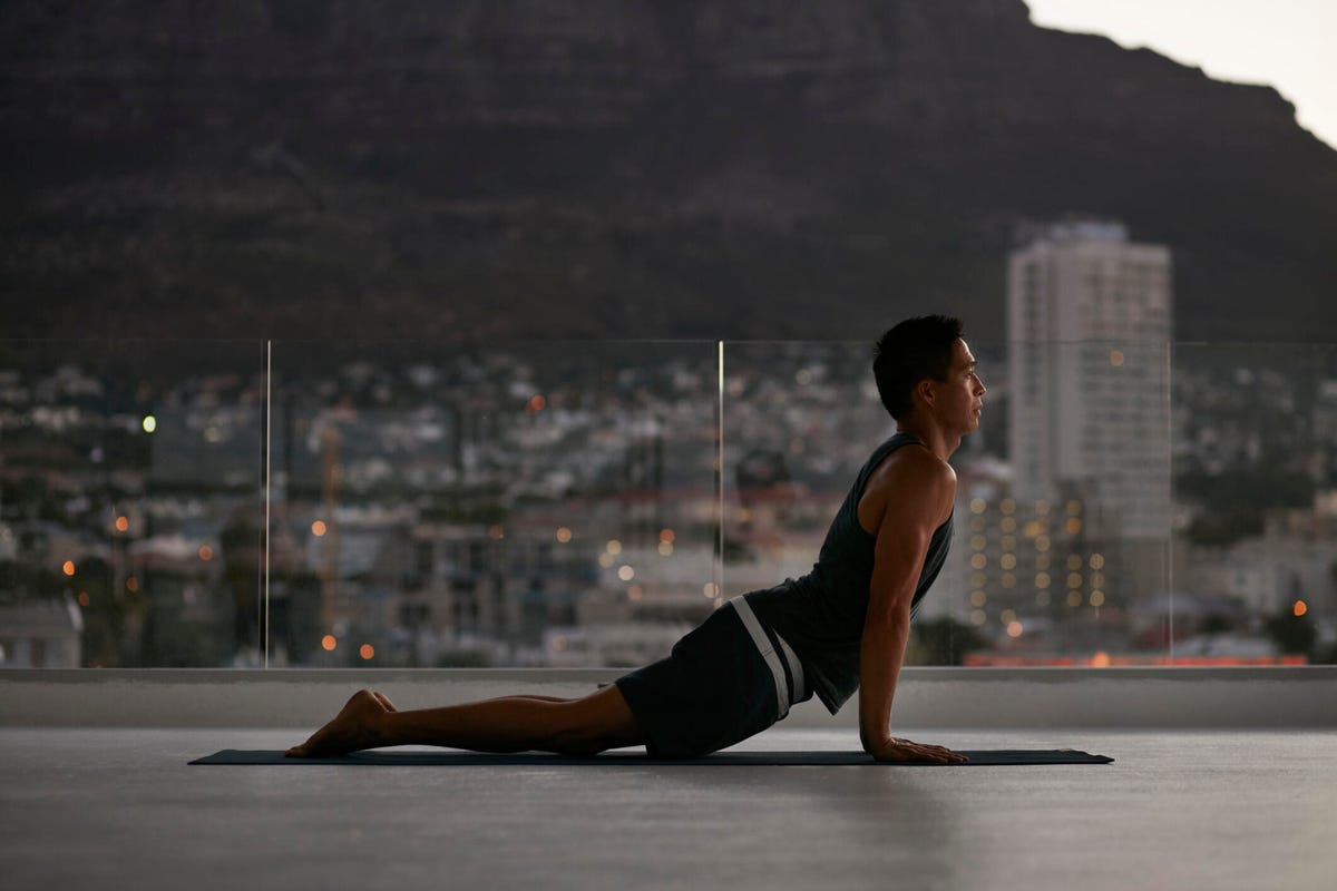 Personne faisant une pose de yoga à l'extérieur avec une ville en arrière-plan