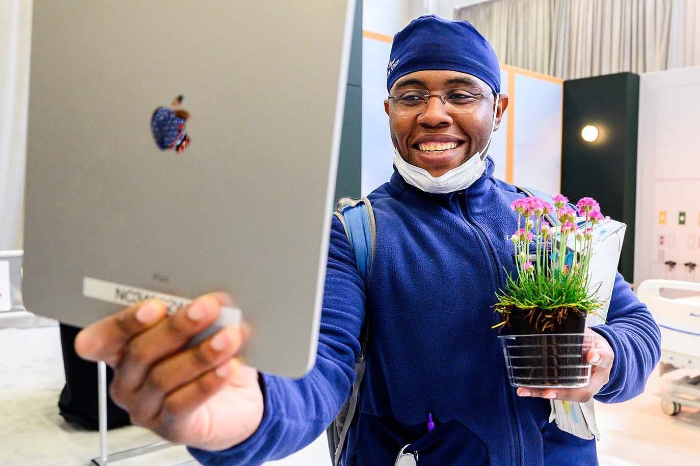 Un professionnel de la santé de l'UCSF sourit en brandissant une plante distribuée aux participants, soulignant l'intégration de l'hôpital avec la nature.