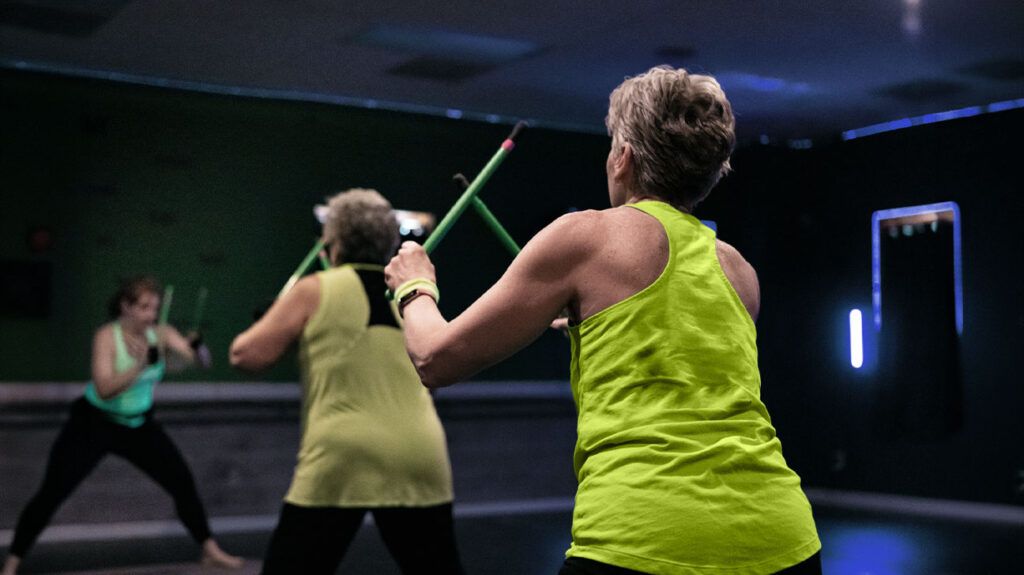 personne âgée portant un débardeur vert fluo faisant de l'exercice à la salle de sport