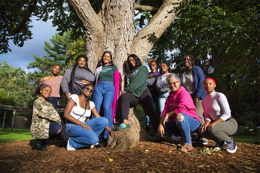 Un groupe d'étudiants et de professeurs posent ensemble à côté d'un grand arbre dans le jardin botanique WJ Beal, sur le campus de la Michigan State University.