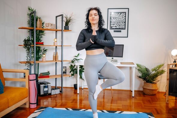 Jeune femme pratiquant le yoga à la maison en gardant l'équilibre debout sur une jambe