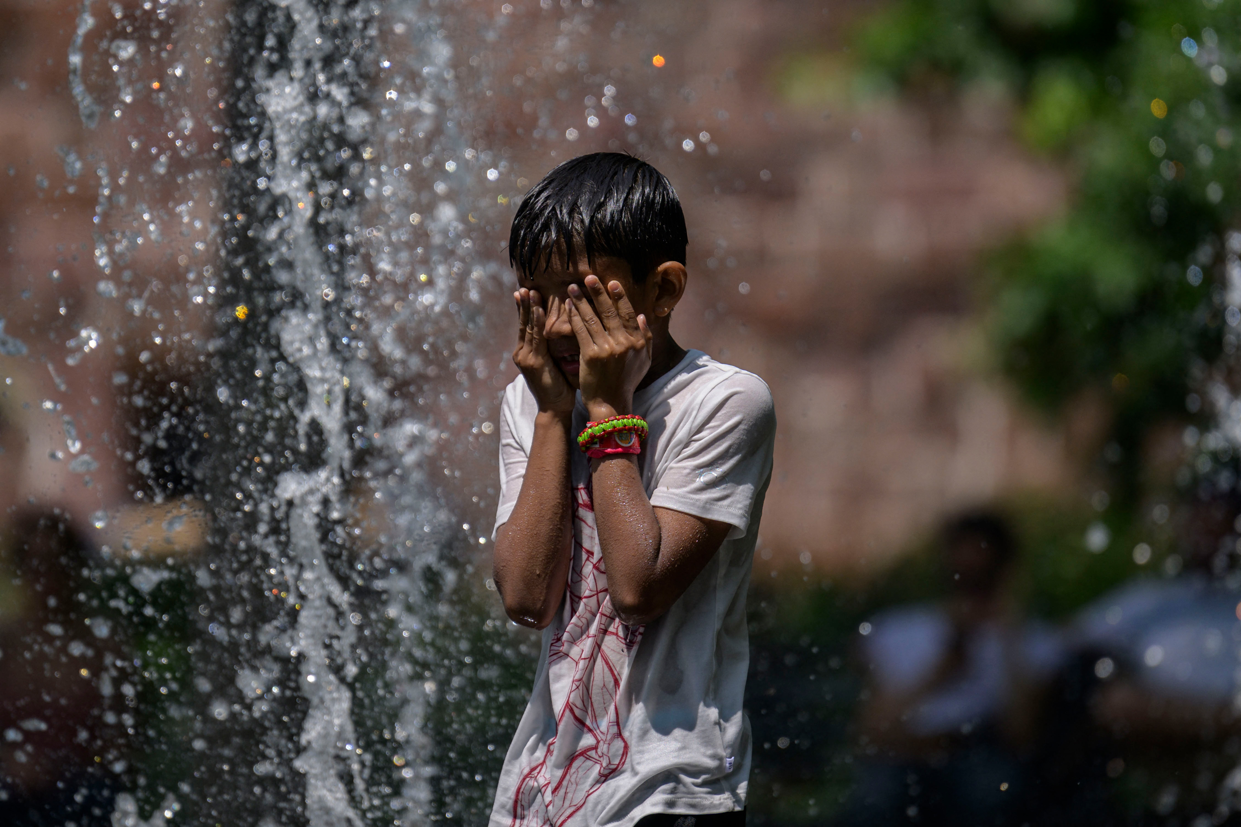 A boy cools off in a public fountain during a heat wave in New York on July 26, 2023. Credit: Angela Weiss/AFP via Getty Images