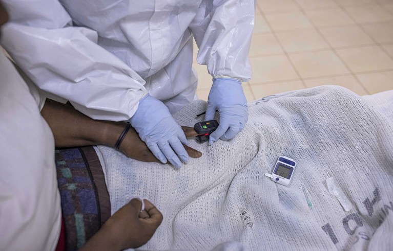 Gros plan d'une infirmière ajustant un oxymètre sur le doigt d'un patient noir Covid-19 à l'intérieur de l'unité de soins intensifs (USI) de l'hôpital Machakos niveau 5, à Machakos, au Kenya.