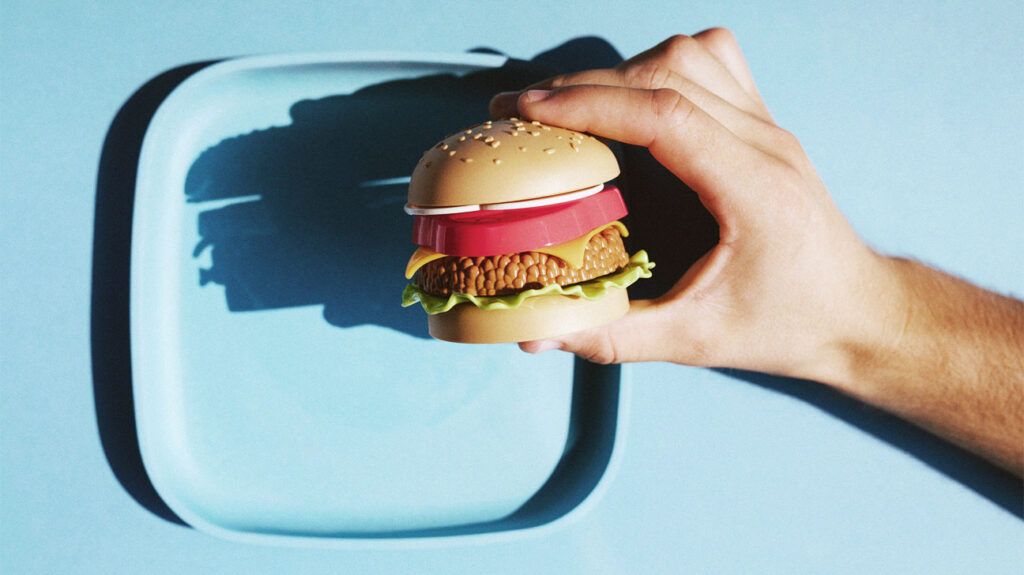 Mini faux burger végétarien tenu dans les mains