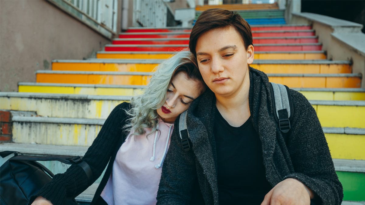 Couple assis en bas des escaliers avec des couleurs LGBT.