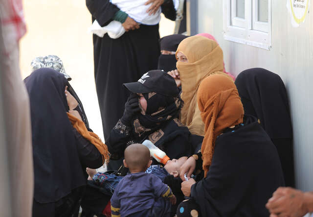 Un groupe de femmes se rassemblent pendant qu'un enfant est nourri au centre de santé de l'IRC.