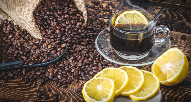 Tasse à café et grains de café torréfiés avec des tranches de citron.
