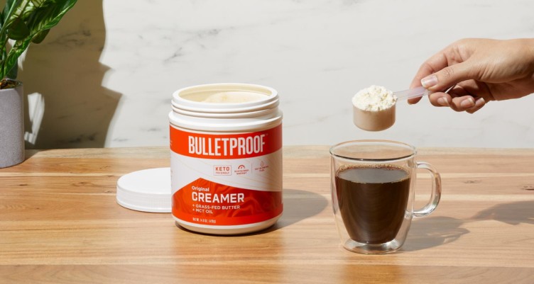 Personne mettant une boule de Bulletproof Original Creamer dans une tasse de café.