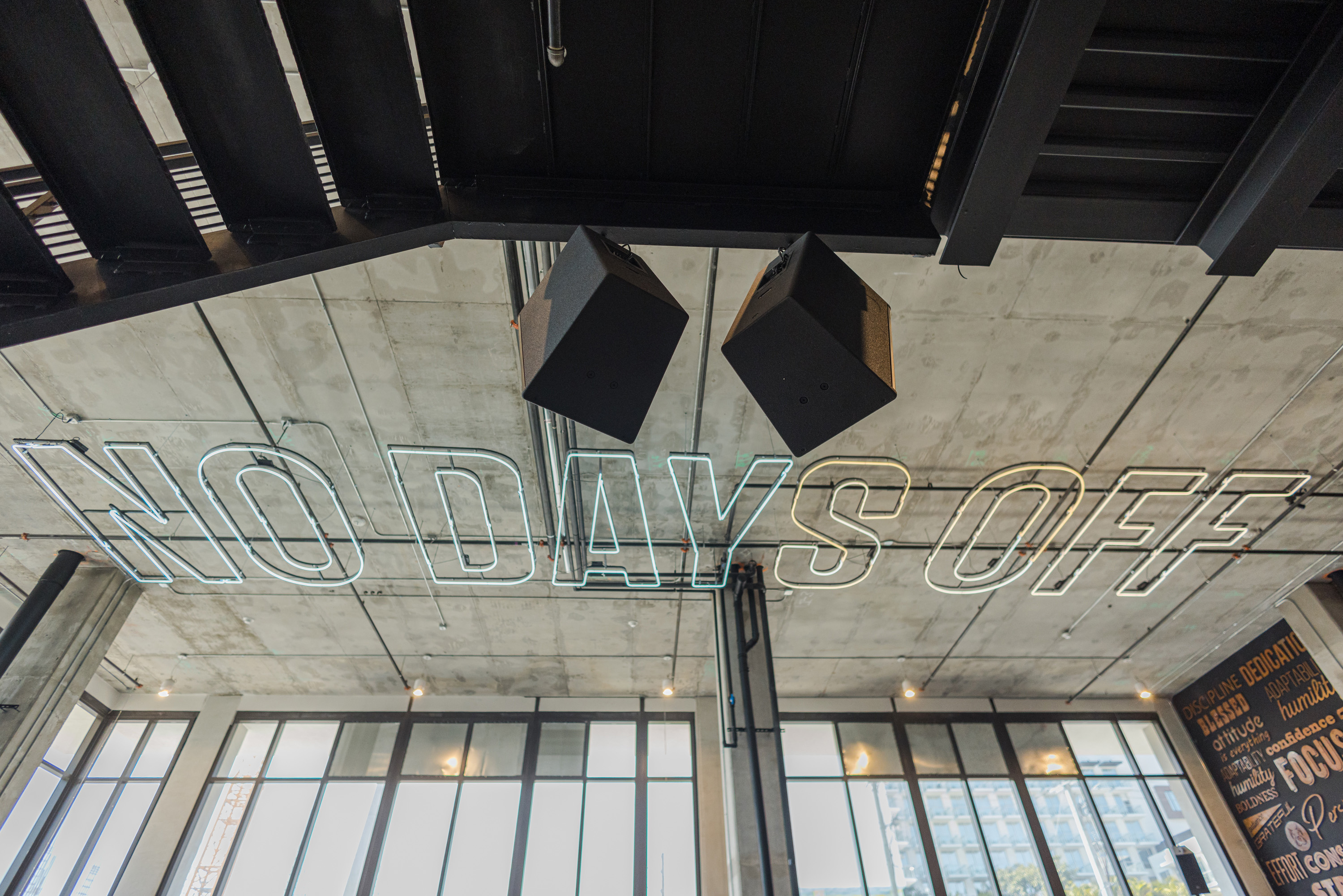 Two DAS Audio speakers in a gym hanging in front of the words No Days Off.