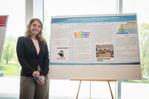Olivia Balbo stands by her research poster about the project with the Hijabi Mentorship Program during the Global Learning Showcase. 